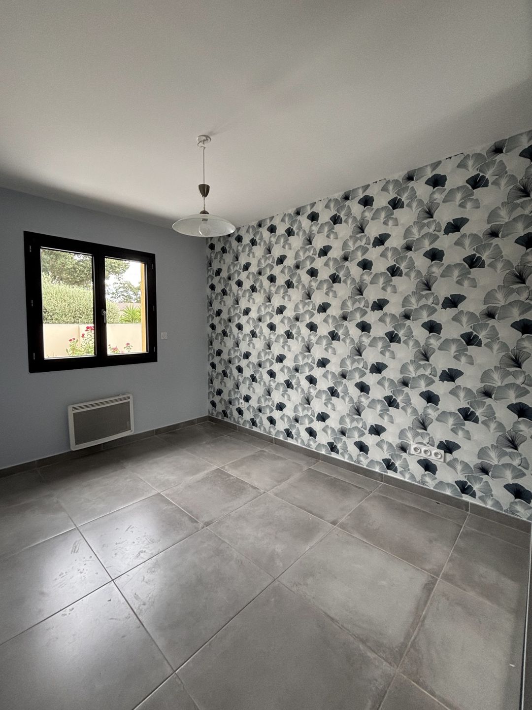 Après travaux à Pia : murs gris bleu et pan de papier peint à motif ginkgo posé par Duflot Peinture