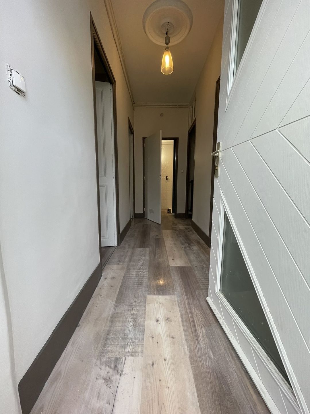 Après travaux à Perpignan : couloir peint en blanc, plinthes et encadrements foncés, parquet posé