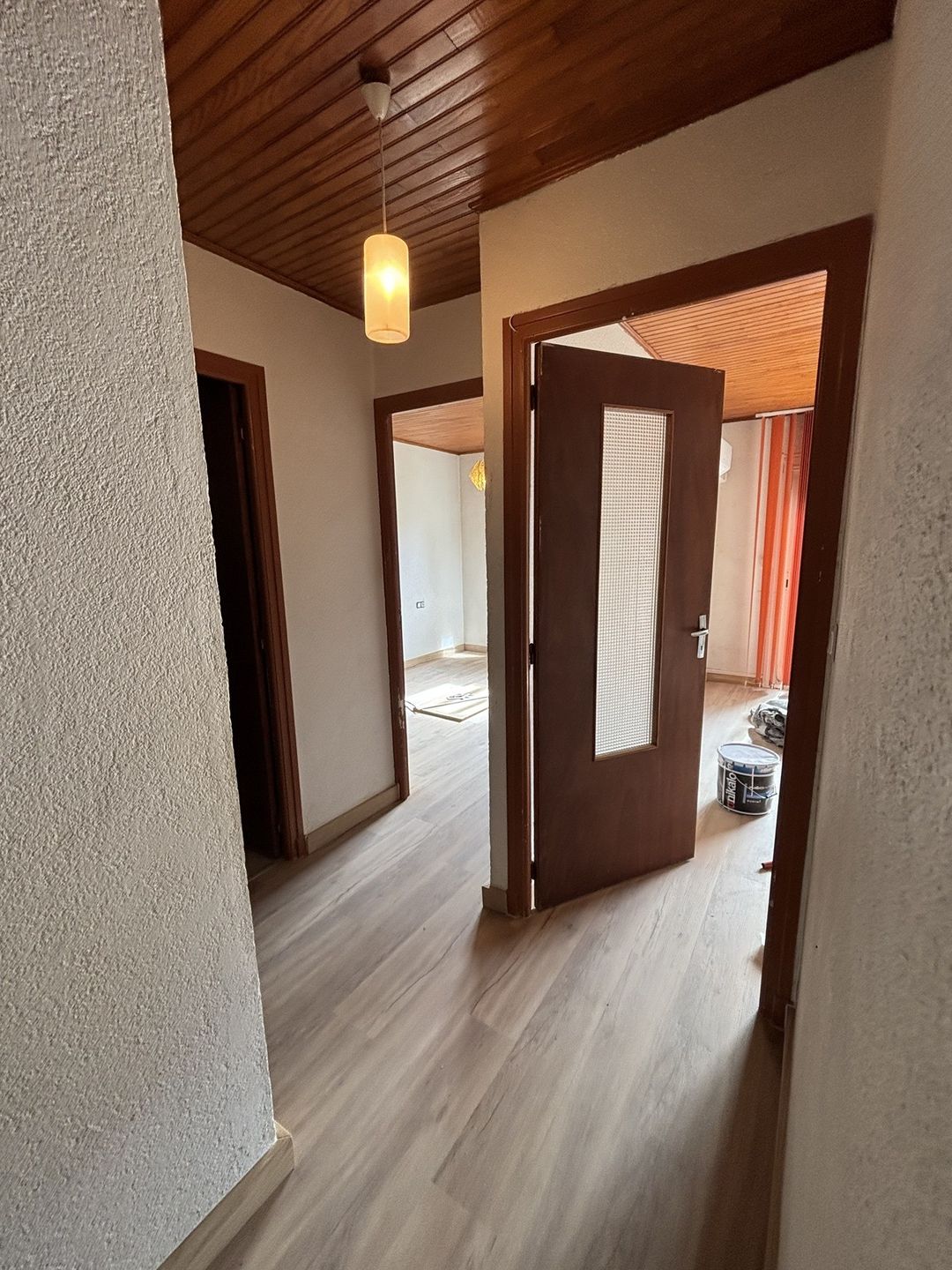 Avant travaux à Saint-Cyprien : couloir aux portes et encadrements en bois foncé, plafond lambris
