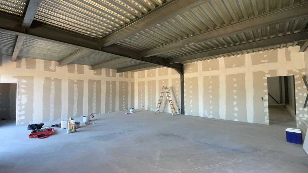 Grand local professionnel en plaques de plâtre : bandes et enduits réalisés avant la mise en peinture, charpente métallique apparente