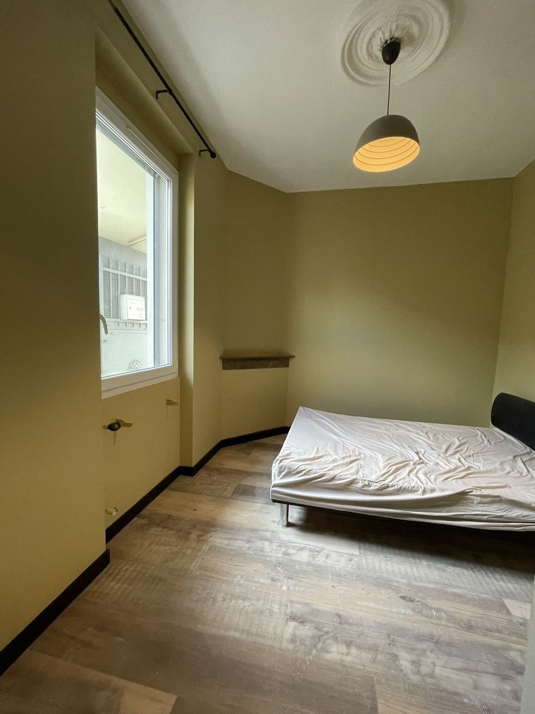 Chambre repeinte à Saleilles : murs vert olive, plafond blanc avec rosace conservée, plinthes noires