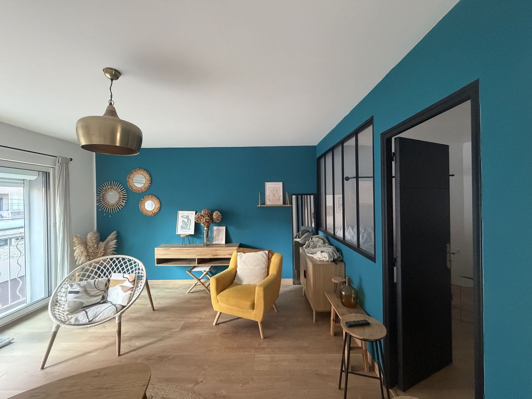 Salon rénové par Duflot Peinture à Perpignan : murs bleu canard, plafond blanc, verrière d’atelier noire et porte peinte en noir